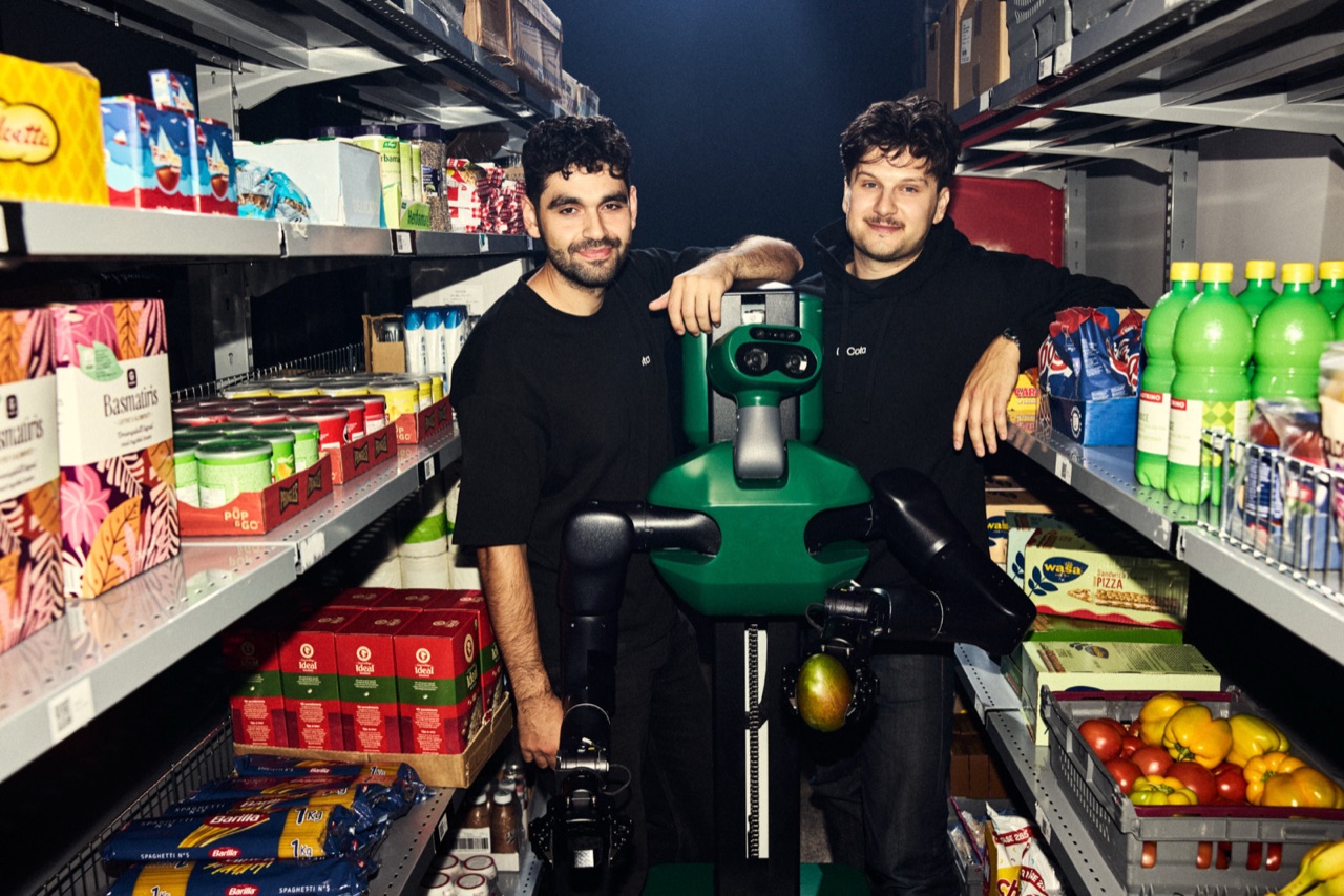 The founders with a Cota robot between the shelves of a store aisle