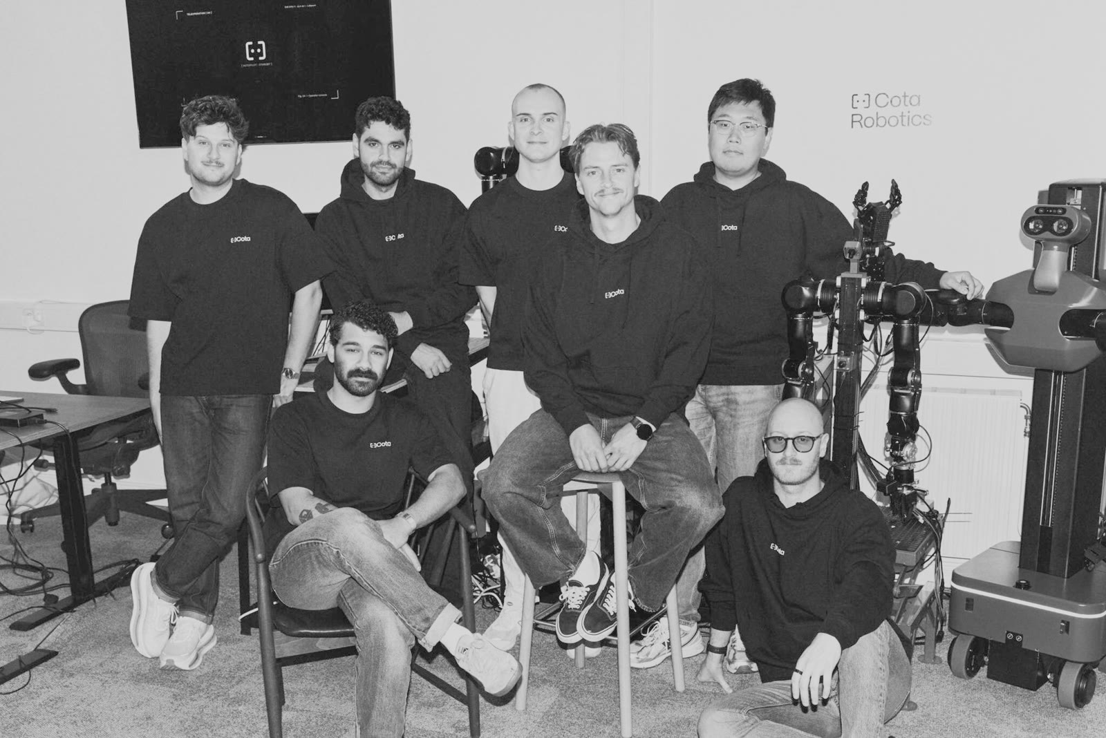 The Cota team in the Stockholm office, beside one of the robots